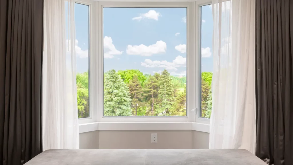 A bed in a room with a large bay window.