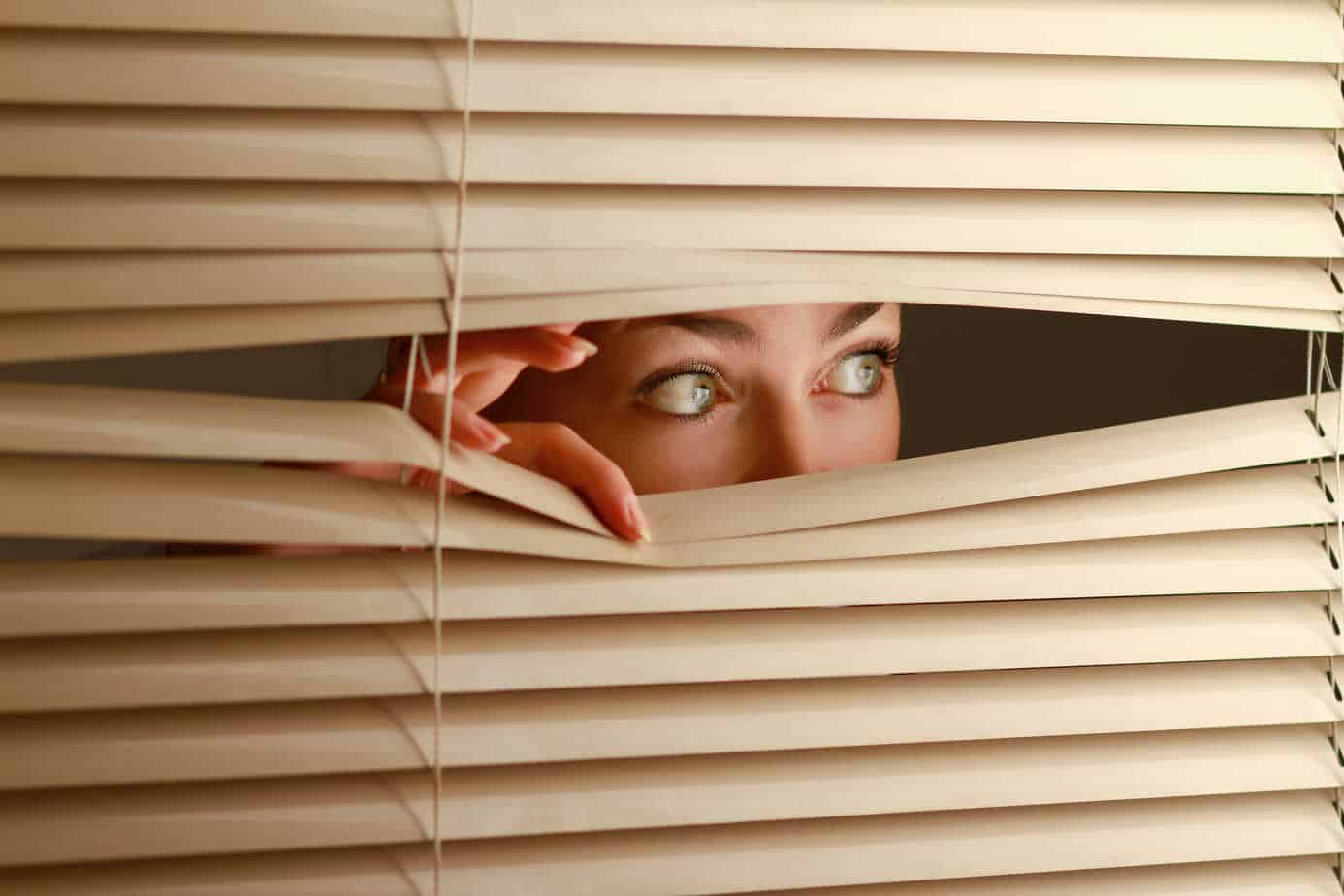 Woman looking through blinds