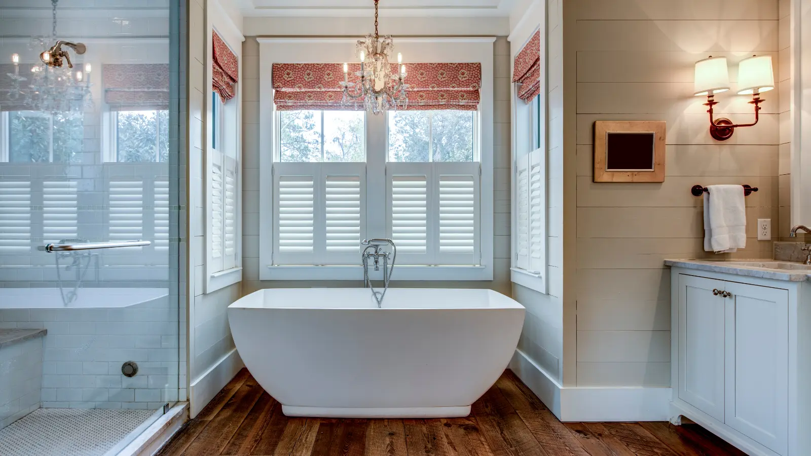 A white bathroom with wooden floors and shutters.