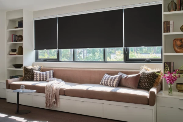 Black roller shades covering the windows in a reading area.