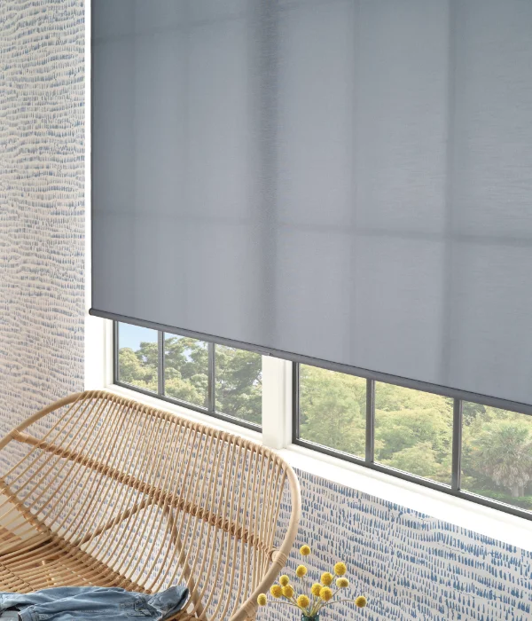 A large roller shade covering the windows of a lounging area.