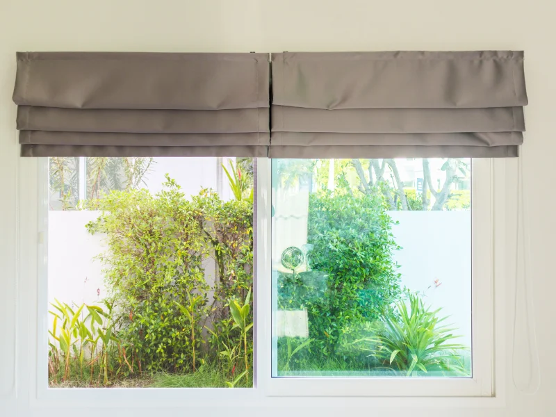 Dual charcoal Roman shades covering a back window.