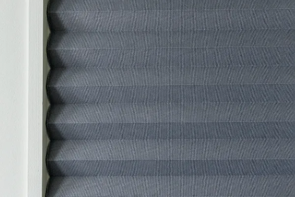 A close up of a window with a blue-gray cellular shade.