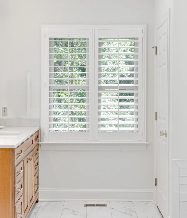 A bathroom with white plantation shutters.