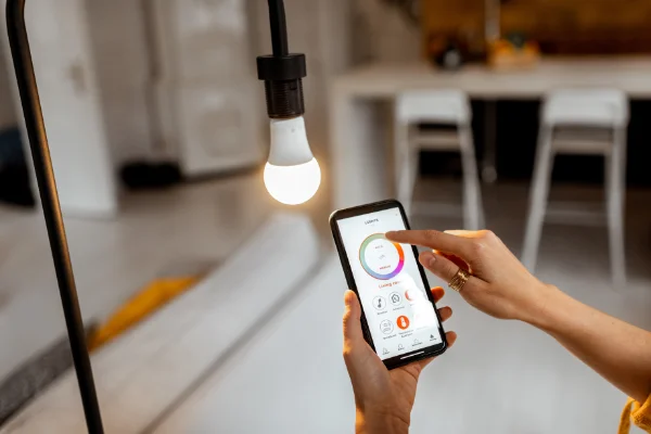 A woman using a smart phone to control a light bulb.