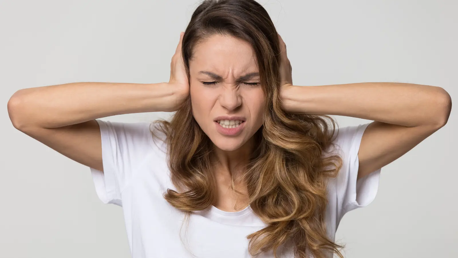 A woman covering her ears with her hands.