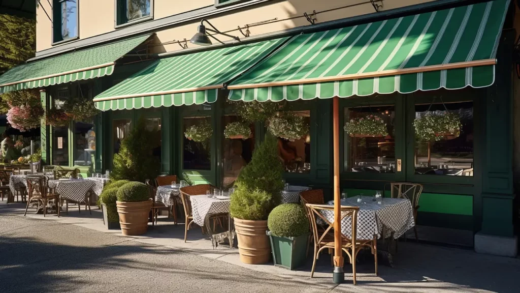 A restaurant with green awnings and tables outside.