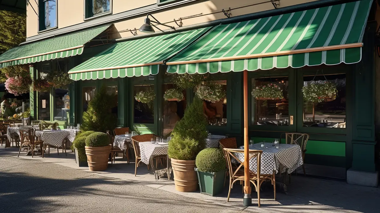 A restaurant with green awnings and tables outside.