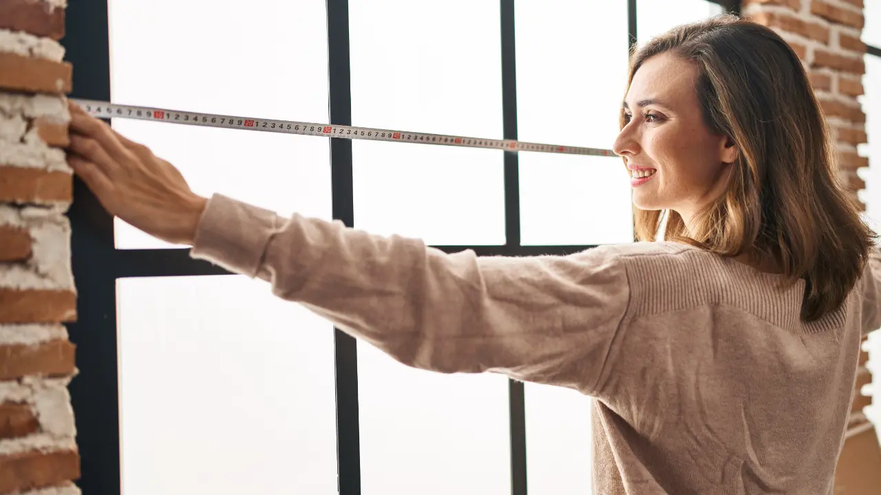 A woman measuring a window.