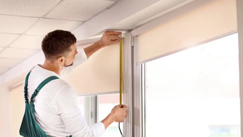 A man measures a roller shade with a tape measure